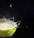 Water splashing over half a lime. Black background. Royalty Free Stock Photo