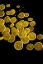 Water splashing on yellow sweet lemon slices isolated on black background. Macro. Close up