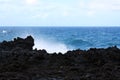 Water spray rising from the Pacific Ocean over jagged, black, volcanic rock at Waianapanapa State Park Royalty Free Stock Photo