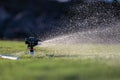 Water sprays from an automatic impact water sprinkler mounted on a custom PVC base. Royalty Free Stock Photo