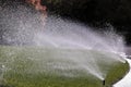Water sprays from an automatic lawn sprinkler system over green lawn Royalty Free Stock Photo