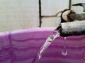 Water squirt or flow coming out from a tap and going to bucket with falling down water drops Royalty Free Stock Photo