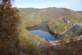 Water storage reservoir surrounded by forest . Seasonal autumnal trees and a lake . Barrage called Urfttalsperre next to Vogelsang Royalty Free Stock Photo