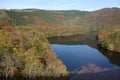 Water storage reservoir surrounded by forest . Seasonal autumnal trees and a lake . Barrage called Urfttalsperre next to Vogelsang Royalty Free Stock Photo