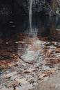 Water stream falling on a quiet pond in a beautiful autumn forest landscape Royalty Free Stock Photo