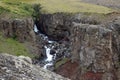 Water stream falls from a red rock. Location: Hengifoss hiking trail, East iceland Royalty Free Stock Photo