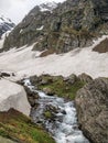 Water stream flowing in between a huge rock on one side and a snow glacier on other side in an epic Indian Himalayan Valley Royalty Free Stock Photo