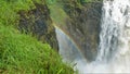 Water streams fall into the gorge. A rainbow formed between the stony slopes.