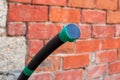 Water supply polyethylene pipe with a plug on the background of a brick wall. Plumbing in a country house