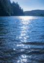 Water surface with reflection of sunbeam. Sparking on water. Blue water of forest lake at sunlight