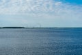 water surface, ripples on the water and clouds in the blue sky. industrial pipes with smoke