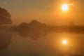 Water surface of river in sunny summer morning with fog and reflection of orange sun. River landscape at sunrise