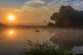 Water surface of river at sunrise with reflection of orange sun. River landscape in sunny summer morning Royalty Free Stock Photo