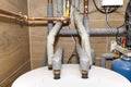 Water tank and gas pipes for a modern gas boiler in a home boiler room, lined with ceramic tiles.