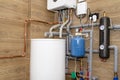 Water tank and gas pipes for a modern gas boiler in a home boiler room, lined with ceramic tiles.