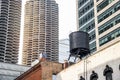 Water tank on the roof of an old brick building surrounded by modern skyscrapers in a downtown district Royalty Free Stock Photo