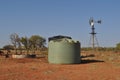 Water tank and windmill in Australian outback with birds in tree ranch station