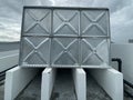 Water tanks holding drinking water standing on concrete plinths. It is located on top of a building