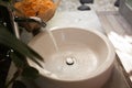 Water tap flow into a sink in open garden bathroom Royalty Free Stock Photo