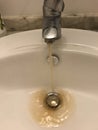 Water tap with running dirty muddy water in a sink Royalty Free Stock Photo