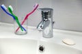 Water Tap, Toothbrushes, Soap and Running Water in a Sink Royalty Free Stock Photo