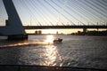 A water taxi is boating very fast during sunset with erasmusbrug bridge on the background