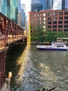 Water taxi on the Chicago River passing restaurant outdoor patio patrons as commuters rush down Lake Street bridge
