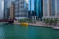 Water taxi docks at stop on Chicago River during weekday lunch break where business people sit on steps and enjoy summer afternoon