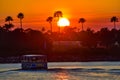 Water taxi sailing on illuminated lake on colorful sunset at Lake Buena Vista area.