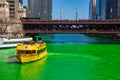 Water Taxi and tour boat on a dyed-green Chicago River as crowds gather on Michicagn Ave