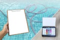 Water tester test kit with blank clipboard over vacuum hose floating in swimming pool background Royalty Free Stock Photo