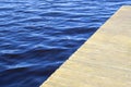 Water texture. Copy space, place for text. Empty wooden pier and blue water surface with small waves. Royalty Free Stock Photo
