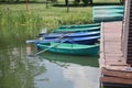 On the water there are multi-colored boats tied to the pier, pleasure boats on the pond, rowing oars, a wooden pier, a Royalty Free Stock Photo