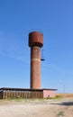 Water tower made of red bricks on blue sky background