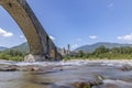 The water of the Trebbia river flows under the Gobbo bridge in Bobbio, Italy, on a hot summer day