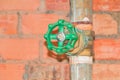 Water valve plumbing joint steel old tap pipe with green knob on brick background Royalty Free Stock Photo