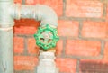 Water valve plumbing joint steel old tap pipe with green knob on brick background Royalty Free Stock Photo