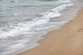 Water washing sand on the beach on overcast day. Detail on small white waves forming. Abstract sea background