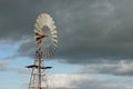 water wind mill next to a large water storage tank on an agricultural sheep stock farm in rural Victoria with dark rain clouds in Royalty Free Stock Photo