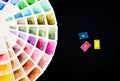 Watercolor color palette on white paper, fanned out, next to three cuvettes with watercolors. On a black background. Royalty Free Stock Photo