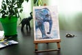 Watercolor drawing of an elephant standing on a small easel.