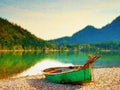 Watercolor effect. Abandoned fishing paddle boat on bank of Alps lake. Morning lake Royalty Free Stock Photo