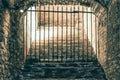 A daunting staircase leading to a passage blocked by an iron grid in a medieval dungeon