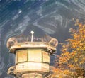 Watchtower of a correctional facility of a prison with a balustrade and two rows of barbed wire rolls in front of a dramatic sky Royalty Free Stock Photo