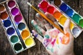 Watercolor paint brush to paint the hand of the artist in multi-colored paint on wood background holding Royalty Free Stock Photo