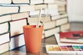 Watercolor paint, brushes well used and sheet of paper on wooden table with stack of books background Royalty Free Stock Photo