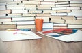 Watercolor paint, brushes well used and sheet of paper on wooden table with stack of books background Royalty Free Stock Photo