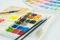 Watercolor palette with brushes and color palette in the background. Graphic design concept choosing color Royalty Free Stock Photo