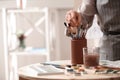 Watercolorist taking brush from holder on table in workshop