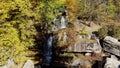 Waterfall in autumn park. Water falls from high stones among trees yellow leaves Royalty Free Stock Photo